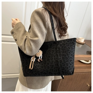 Detailed back view of a dark leopard print tote bag with a brown fuzzy charm accessory