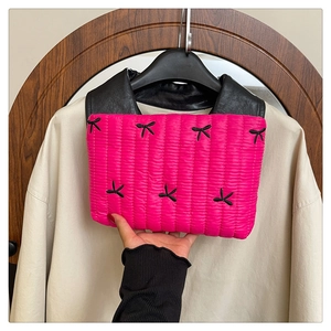 Detalle del neceser acolchado rojo rosa con lazos negros y asa de cuero suave