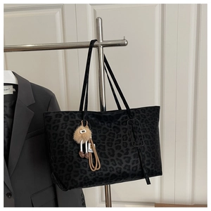 Detail of leopard print tote bag with plush charm and long shoulder straps