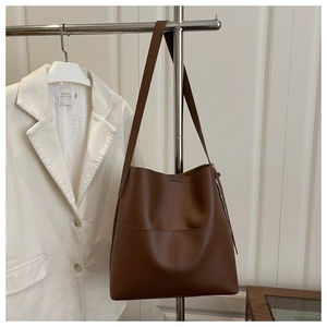 Close-up of a brown leather bucket bag hanging on a rack with decorative stitching