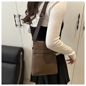 Detail of the brown pebble leather texture and gold hardware on the adjustable strap