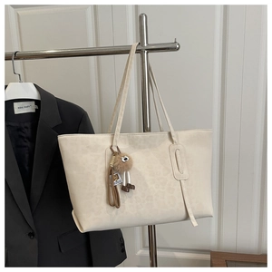 Detail of beige leopard print tote bag with a cute eye charm hanging on a hanger
