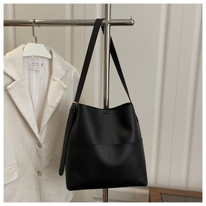 Detail of a black matte leather tote bag with vertical stitching and adjustable strap