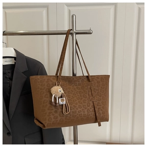 Detailed view of large leopard print tote bag with soft texture and plush charm