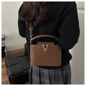 Detail of leopard print tote bag with gold V logo and detachable shoulder strap on model