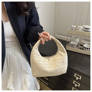 Gros plan du sac hobo croissant en paille tressée crème avec texture détaillée et poignée