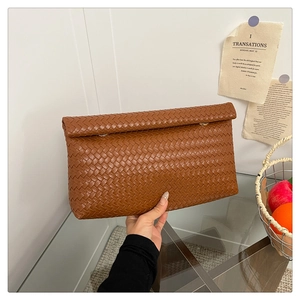Close-up of brown hand-woven texture on the high-quality synthetic leather envelope bag