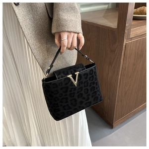 Detail of black leopard print handbag with a gold V-shaped buckle and plush suede texture