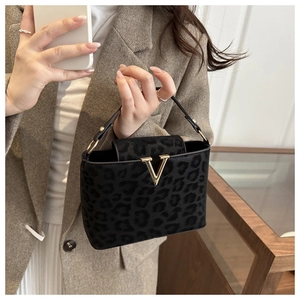 Detail of leopard print handbag with gold V logo held by a model in a brown blazer