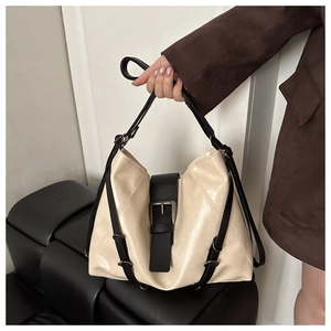 Detail of minimalist cream tote bag with black decorative strap and metallic hardware