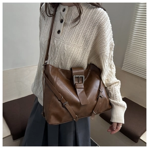 Detail of a large dark brown leather tote bag with a decorative metal buckle on a model