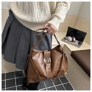 Brown vintage large tote bag with decorative metal buckles shown on shoulder for commute
