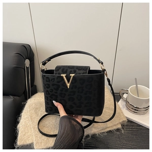 Detail of leopard print handbag featuring a gold V-shaped buckle on a matte texture