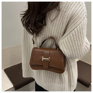Sac bandoulière marron avec boucle en métal H et texture cuir premium sur modèle