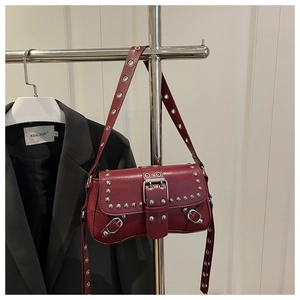Macro detail of wine red punk baguette bag with silver rivets and metal buckle strap