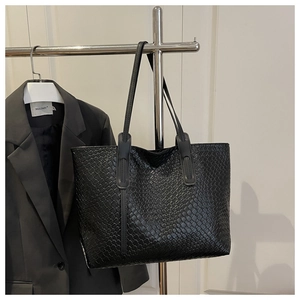 Gros plan sur la texture en cuir tressé noir et la bandoulière renforcée du sac cabas