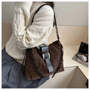 Detail of dark leopard print tote bag with leather strap and silver buckle on shoulder