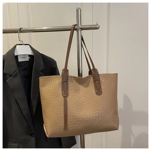 Détail du sac cabas tressé kaki montrant la texture dense et les anses marron foncé