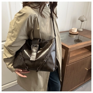 Detail of vintage dark brown leather tote bag featuring a large metal buckle and side straps