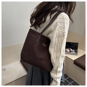 Detailansicht der braunen Shopper-Tasche mit FASHION-Lederetikett und Wildleder-Textur