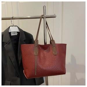 Détail du cabas tissé bordeaux avec lanières en cuir marron et intérieur spacieux