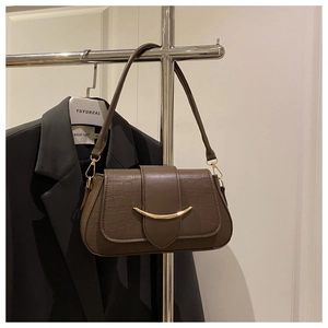Détail du sac à bandoulière marron texture crocodile avec boucle dorée en demi-lune