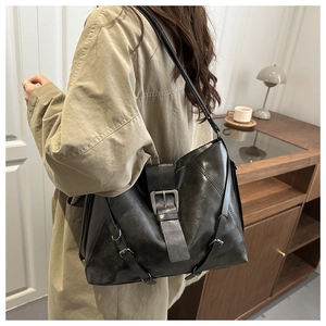 Detail of a vintage black leather tote bag with silver buckles and adjustable shoulder strap