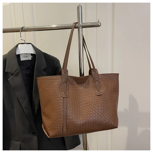 Gros plan d'un sac cabas marron à texture tressée suspendu pour un style professionnel chic