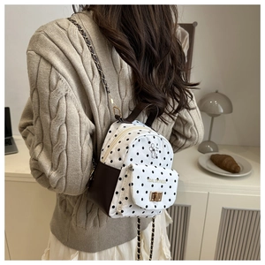 Polka dot mini backpack with chain strap shown on model in a cozy indoor setting