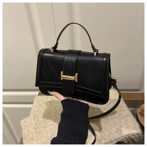 Detail einer schwarzen Steppledertasche mit goldenem Metallverschluss und Griff