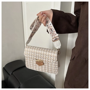 Detail of checkered shoulder bag featuring wide embroidered strap and gold clasp