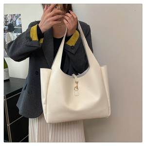 Close-up of cream tote bag featuring a gold metal hook closure and smooth leather texture