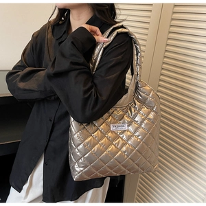 Detail of silver quilted tote bag with diamond pattern and fashion label on front