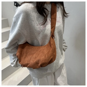 Close-up of brown suede crescent bag featuring pleated base and knotted wide strap