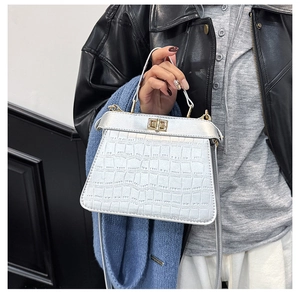 Detalle de bolso plateado con relieve de cocodrilo, cierre dorado y acabado metálico