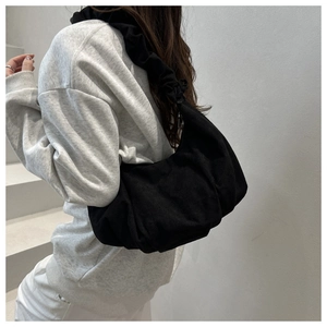 Detail view of the pleated black cloud bag with textured fabric and wide ruched strap