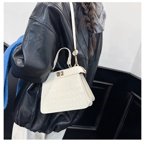 Nahaufnahme der weißen Handtasche mit Krokodilprägung und goldenem Schloss an einem Model