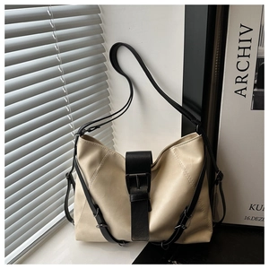 Detail view of cream soft leather tote bag showing black contrast strap and buckle accents