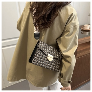 Detail of tweed crossbody bag featuring gold buckle and vintage patterned strap
