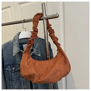 Detail of tan suede crescent bag featuring a unique ruched wide shoulder strap