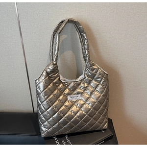 Detailed view of golden quilted tote bag with metallic luster and fashion label