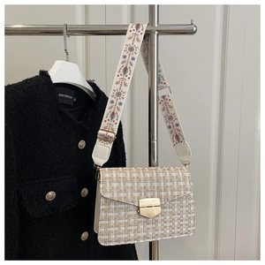 Close-up of tweed handbag with vintage embroidered strap and golden metallic clasp