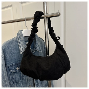 Detail of black crescent hobo bag with pleated shoulder strap on a metal hanger