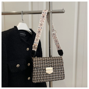 Detail of tweed crossbody bag with gold lock and wide floral embroidered strap