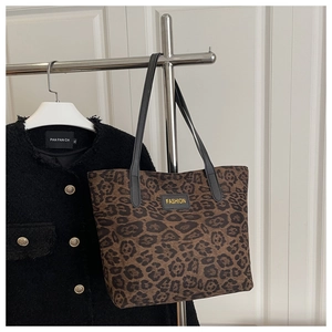 Nahaufnahme der Totebag mit Leopardenmuster und FASHION-Label auf einer Tweed-Jacke