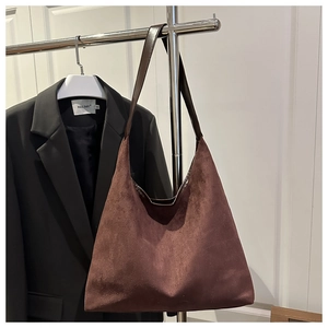 Close-up of a large coffee suede tote bag with leather straps on a minimalist hanger