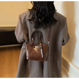 Détail de la texture cuir marron foncé et du fermoir rotatif en métal argenté du sac seau