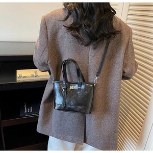 Vue détaillée du sac bandoulière en cuir verni noir avec fermoir argenté sur un mannequin