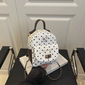 Polka dot mini backpack with gold hardware and brown leather accents on a chair