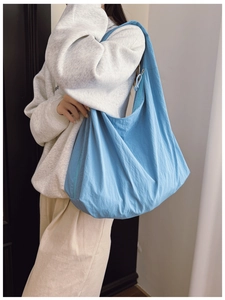 Detail view of large sky blue nylon tote bag with side zipper and drawstring decoration